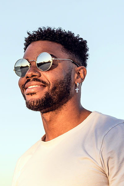 Un jeune homme afro portant ses lunettes de soleil dans un paysage ensoleillé 